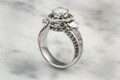Think of this luxury engagement ring as a temple for your inner goddess.  This unique design has a halo of diamonds around the prong-set center stone, two side stones
