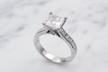 This classic cathedral style engagement ring is a timeless work of art. The princess cut center stone is prong set above a band of channel set princess cut accent diamonds. 