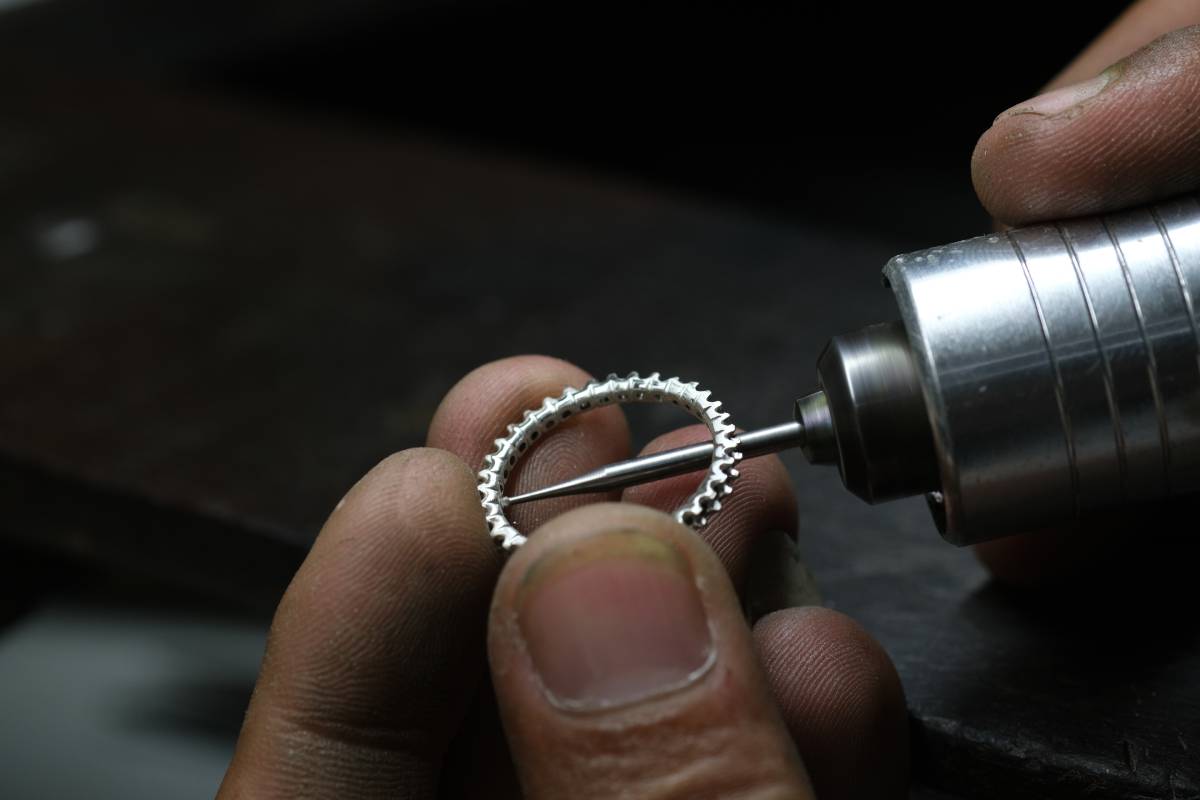 A jeweler utilizes a hand-engraving drill to enlarge holes and add details to a wedding ring.