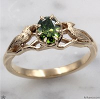 A gold ring featuring a green gemstone and intricate designs.