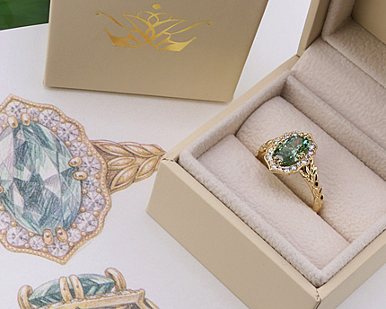 a unique engagement ring in a box next to a sketch of the ring