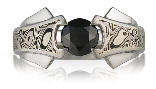 A silver ring with a large black gemstone is displayed prominently against a white background