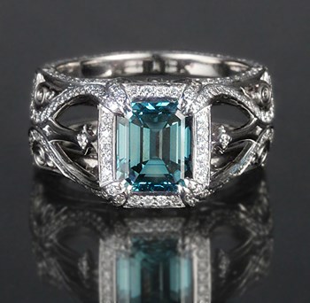A silver ring with an intricate design featuring a large blue gemstone.