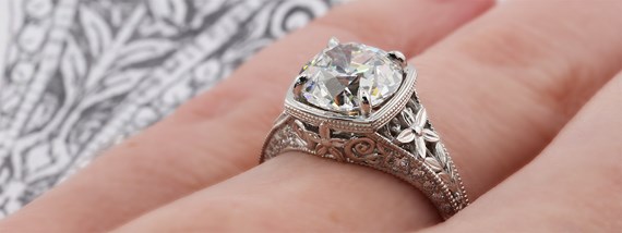 Final custom engagement ring on hand with sketch behind